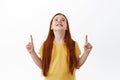 I want it. Little cute girl with freckles and long red hair pointing, looking up with desire and dreamy face, dreaming Royalty Free Stock Photo