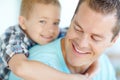 I want a piggyback ride, dad. A cute young boy giving his dad a hug and smiling at the camera. Royalty Free Stock Photo