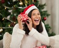 I want to know whats in here. a young woman holding a gift box at home during Christmas time.