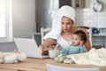 I was hoping youd have some ideas for me. a woman eating rusks while working on her laptop and holding her baby on her