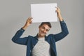 I was just thinking out loud about this. Studio portrait of a young man holding a blank placard against a grey Royalty Free Stock Photo