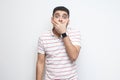 I will be quiet. Portrait of shocked bearded young man in striped t-shirt standing closing his mouth with hands and looking at