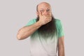 I will be quiet. Portrait of shocked middle aged bald man with long beard in light green t-shirt standing, covering his mouth, Royalty Free Stock Photo