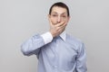 I will be quiet. Shocked handsome bristle businessman in classic blue shirt standing looking at camera with big eyes and covering Royalty Free Stock Photo