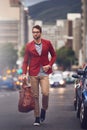 I will get there one way or another. Shot of a handsome young man walking in the road while carrying his bag looking Royalty Free Stock Photo