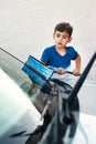 I will make sure this window is sparkling clean. a focused and determined little boy washing a car window outside at