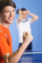I won! Happy young table tennis player gesturing while his opponent standing on the background with head in hands Royalty Free Stock Photo