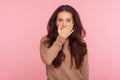 I won`t say anyone! Portrait of frightened young woman with long brunette hair covering mouth with hand, looking shocked Royalty Free Stock Photo