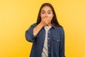 I won`t tell anyone! Portrait of terrified girl in denim shirt covering mouth and looking frightened, holding breath