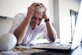 I worked hours on this. a mature man feeling stressed after spilling coffee on his paperwork and laptop in the kitchen Royalty Free Stock Photo