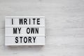 `I write my own story` words on a light box on a white wooden surface, top view. From above, overhead, flat lay. Copy space