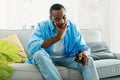 I& x27;m broke. Sad african american man bankrupt showing his empty wallet and looking at it, sitting on sofa at home Royalty Free Stock Photo