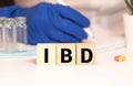 IBD Inflammatory Bowel Disease acronym cut from newspaper on white handmade paper texture