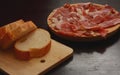 Iberian or Serrano ham on a wooden plate, accompanied with bread. Typical Spanish dish Royalty Free Stock Photo