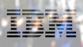 IBM logo on a glass against blurred crowd on the steet. Editorial 3D rendering Royalty Free Stock Photo