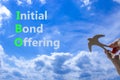 IBO initial bond offering symbol. Concept words IBO initial bond offering on beautiful blue sky clouds background. Wooden bird.