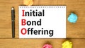 IBO initial bond offering symbol. Concept words IBO initial bond offering on beautiful white note. Beautiful wooden table wooden