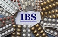 IBS - acronym on a white sheet against the background of tablet plates