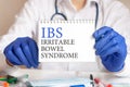 Doctor holding a tablet with text: IBS. IBS - Irritable Bowel Syndrome, medical concept.