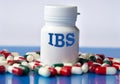 IBS - medical acronym on a white jar against the background of randomly scattered tablets