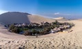 Ica oasis desert. Lagoon in the middle of dunes surrounded by trees and some houses.