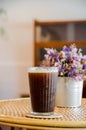 ice americano coffee in tall glass on wooden table with violet flower vase Royalty Free Stock Photo