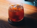 Ice black coffee in a cup on wooden table and Coffee shop blur background with old wood grain image