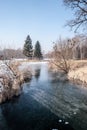 Ice-bound creek with pond on the background, trees and clear sky in Karvina city in Czech republic