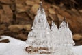 Ice castles against a background of brown rocks.