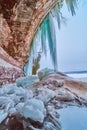 Ice cave opening on rocks and lake with blue icicles Royalty Free Stock Photo