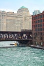 An ice chunk covered, frozen Chicago River is aqua blue and runs through Chicago Loop while el train passes over water Royalty Free Stock Photo