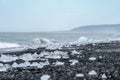 Ice chunks washed up on rocky black sand beach, as waves from the Atlantic Ocean crash on shore. Diamond Beach Iceland Royalty Free Stock Photo