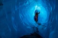 Ice climber in all orange looking up at narrow section of an ice cave. Light shines through the thin ice to illuminate the old Royalty Free Stock Photo