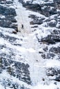 Ice climber climbs on icefall during a snowfall