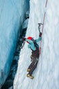 Ice climber swinging ice tool inside a deep crevasse on a glacier in Alaska