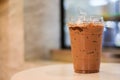 Ice cocoa or coffee in plastic glass on wooden table for relax.