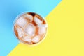 Ice coffee in glass glass cup tube on yellow and blue background, top view. Royalty Free Stock Photo