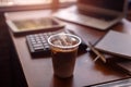 Ice coffee on office workplace with laptop, calculator, book and document on wood table