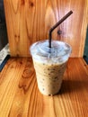 Ice coffee in plastic cup and brown tube on the wooden table Royalty Free Stock Photo