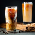 Ice coffee in a tall glass with cream poured over, ice cubes and beans on a old rustic wooden table. Cold summer drink with tubes Royalty Free Stock Photo