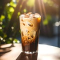 Ice coffee in a tall glass with cream poured over, ice cubes and beans on a table. Glass of a iced coffee with cream milk. Cold