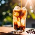 Ice coffee in a tall glass with cream poured over, ice cubes and beans on a table. Glass of a iced coffee with cream milk. Cold