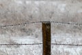 Ice covered barb wire fence and wooden post Royalty Free Stock Photo