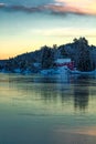 Ice covered fjord and colorful sky reflected in the ice. Winter landscape with islands, huts, sea, snowy rocks, blue sky Royalty Free Stock Photo