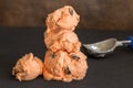 Ice cream balls stacked on black table with icecream scoop defocused in background - Rum and raisin flavour