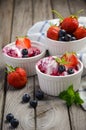 Ice cream with blueberries and strawberries in white bowl on rustic wooden background Royalty Free Stock Photo