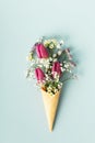 Ice cream cone with beautiful flowers on blue background flat lay Royalty Free Stock Photo