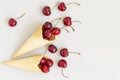 Ice cream cone filled with cherries on a grey light background. Fresh cherry in a waffle cone. Summer concept. Royalty Free Stock Photo