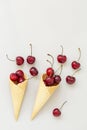 Ice cream cone filled with cherries on a grey light background. Fresh cherry in a waffle cone. Summer concept. Royalty Free Stock Photo