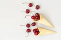 Ice cream cone filled with cherries on a grey light background. Fresh cherry in a waffle cone. Summer concept. Royalty Free Stock Photo